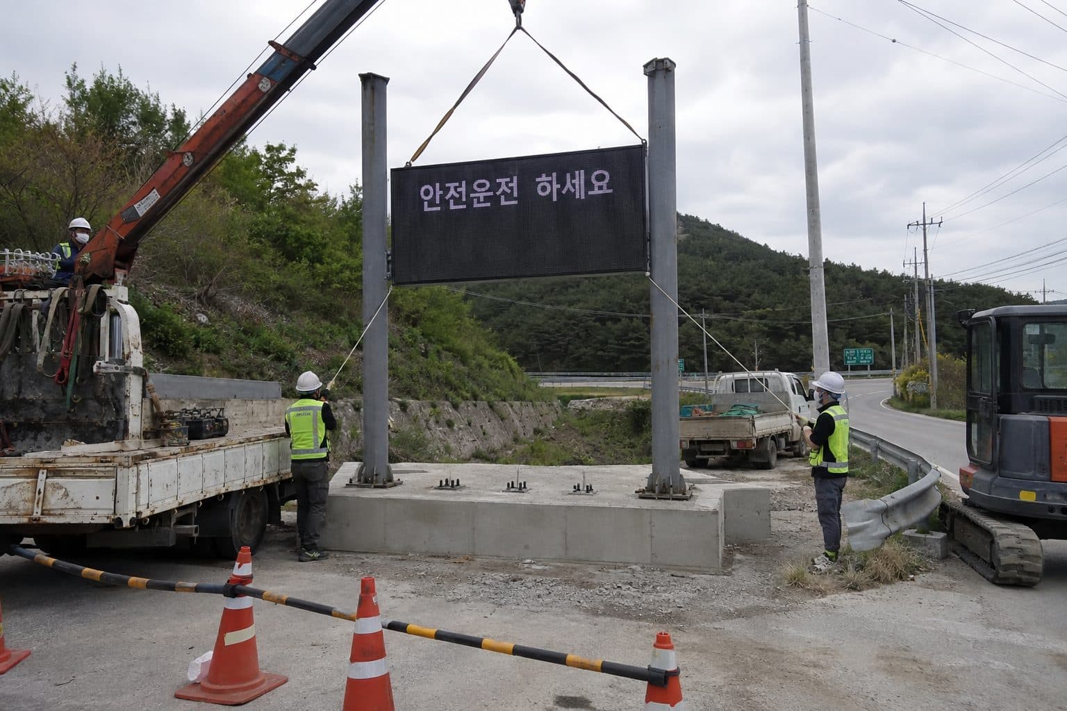 도로변 H형강 지주에 크레인으로 구조물을 세우는 장면